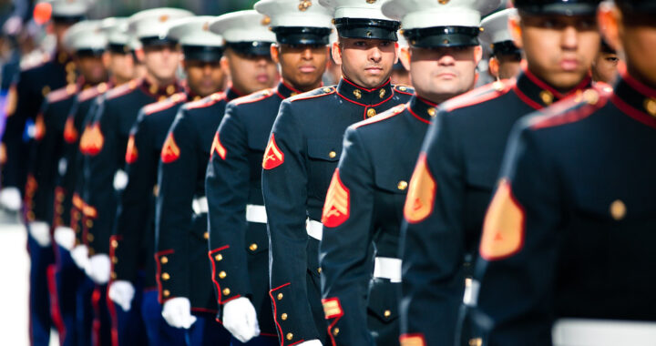 A formation of uniformed marines stands at attention in what appears to be a ceremonial event or parade.